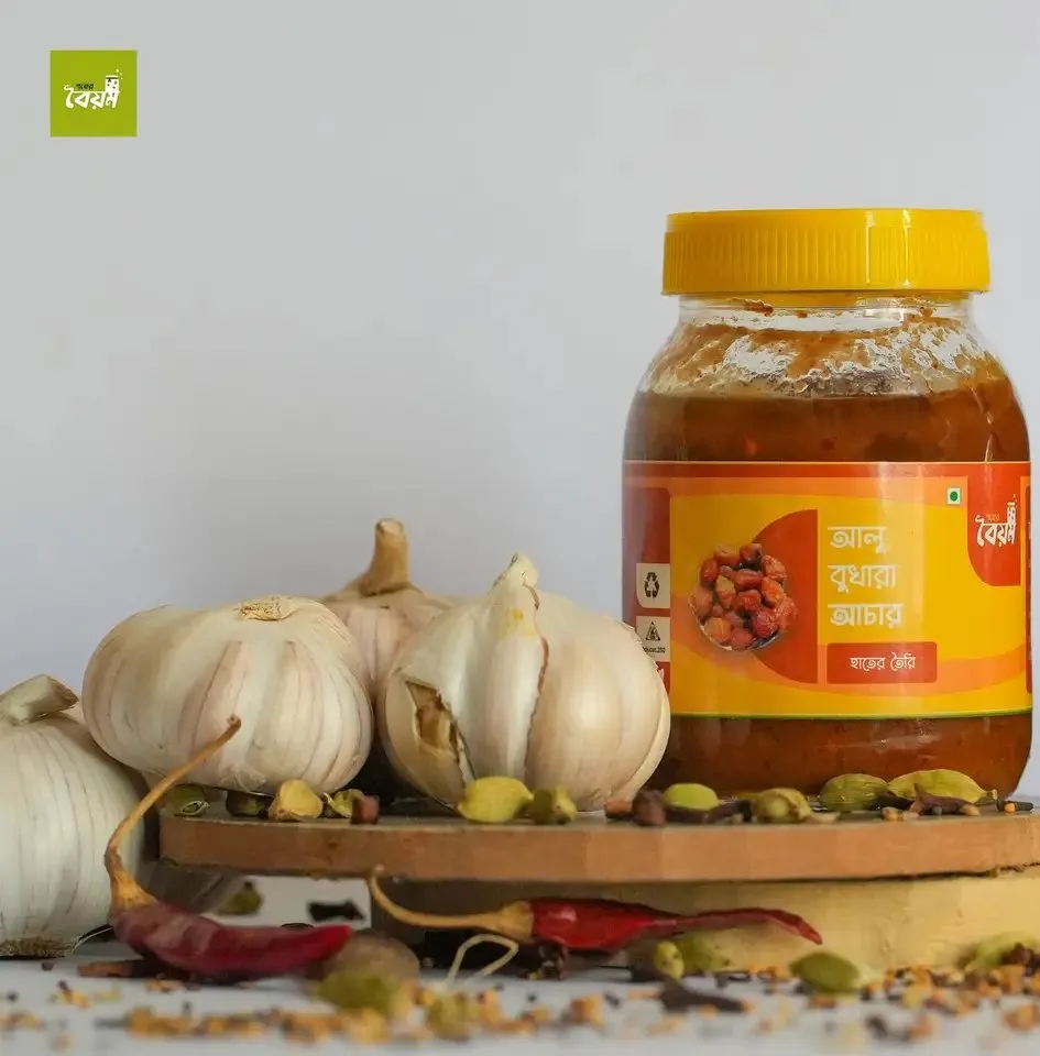A jar of pickle with an orange and yellow label from a brand Maruf designed, next to garlic and spices